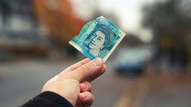 man holding a £5 note out